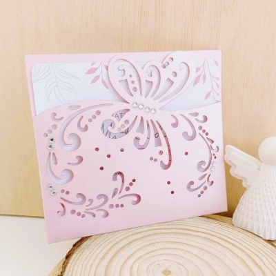 Cartão rosa com borboleta recortada e figura branca de anjo ao lado
