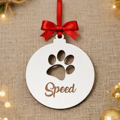 Enfeite de Natal redondo branco em madeira com recorte em forma de pata e texto Speed, com fita vermelha e laço.