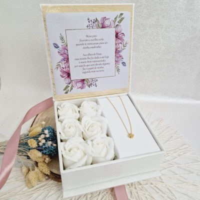 Caixa branca com flores artificiais e colar com pingente de trevo