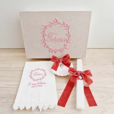 Conjunto de batismo com toalha branca bordada, velas com laços vermelhos e caixa bege bordada.
