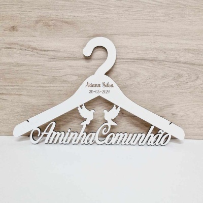 Cabide branco com texto 'A minha Comunhão' e nome 'Ariana Silva 26-05-2024' em madeira clara