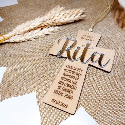 Cruz de madeira com nome Rita em metal prateado e inscrição em português sobre tecido bege e trigo seco