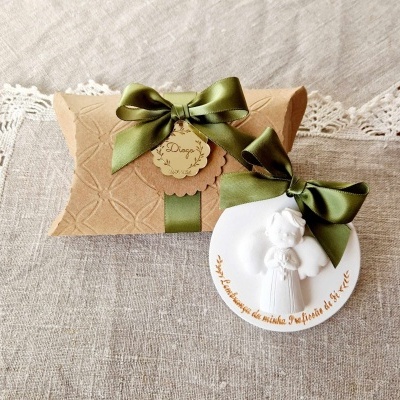 Conjunto de caixa de presente castanha com fita verde e ornamento branco redondo com anjo em relevo.