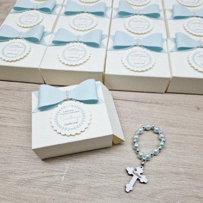 Caixas brancas com laços azuis claros e terço azul claro com crucifixo branco