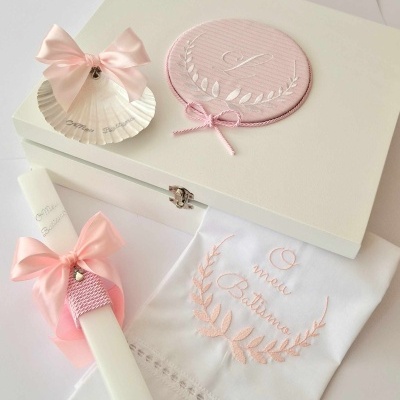 Caixa branca decorativa com concha, vela e pano para batismo, em rosa e branco.