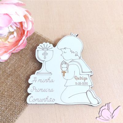 Peça decorativa branca com criança ajoelhada e texto da Primeira Comunhão