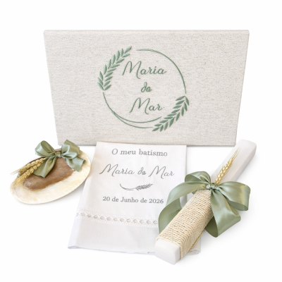 Conjunto para batismo com vela branca, toalha bordada e caixa decorativa com texto e folhas verdes.