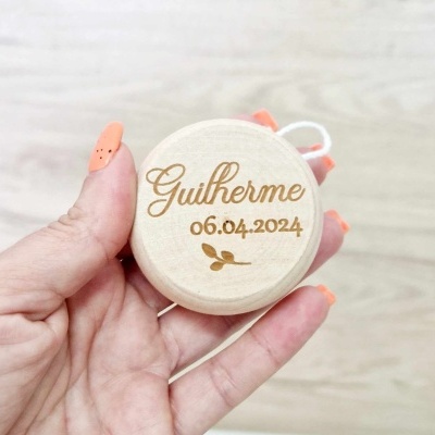 Objeto redondo em madeira com gravação do nome Guilherme e data 06.04.2024