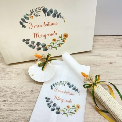 Conjunto de batismo com caixa branca, toalha e vela decorados com flores e texto em português