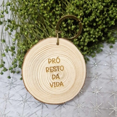 porta-chaves redondo em madeira clara com inscrição dourada sobre tecido branco com padrão de estrelas prateadas