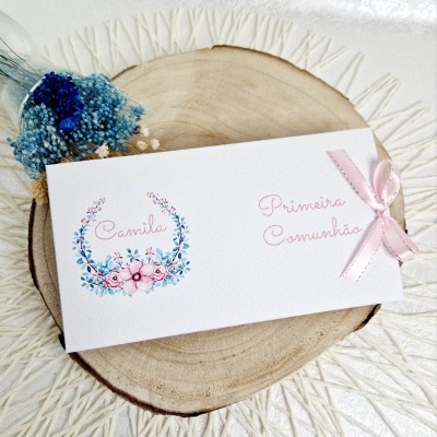 Convite branco decorado com flores e laço rosa sobre base de madeira com flores secas ao lado