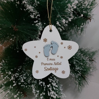 Ornamento estrela branca com pés azuis e texto de Natal pendurado em árvore