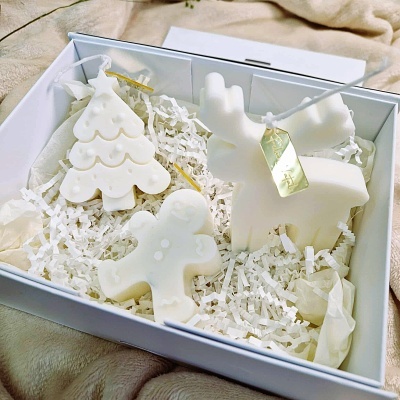 Três velas decorativas brancas em caixa branca com enchimento de papel