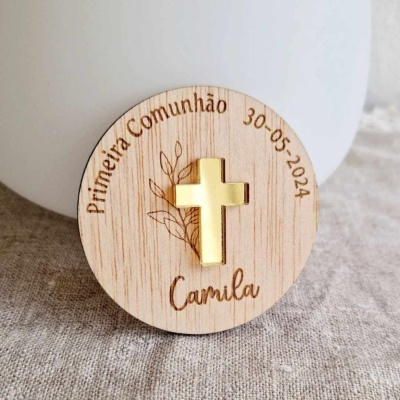Disco redondo em madeira clara com cruz dourada e texto gravado