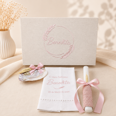 Conjunto de batismo com caixa bege, lenço branco com texto, vela com fita rosa e porta-anel em concha.