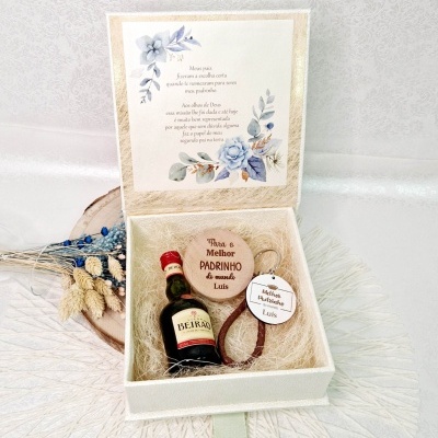 Caixa de presente branca aberta com garrafa de Beirão, porta-chaves de madeira e decoração seca
