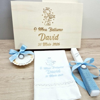 Conjunto de batismo com caixa de madeira, vela branca com fita azul, pano branco bordado e concha decorada.