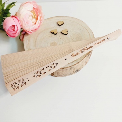 Leque de madeira decorado com gravação e recortes, com corações de madeira e flores rosas ao lado