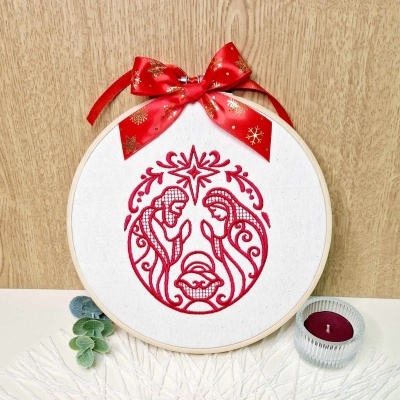 Bastidor de bordado com desenho natalício em vermelho e laço vermelho com flocos dourados no topo