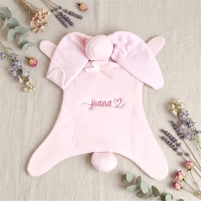 Roupa rosa para bebé com o nome joana bordado e um coração, rodeado por flores secas.