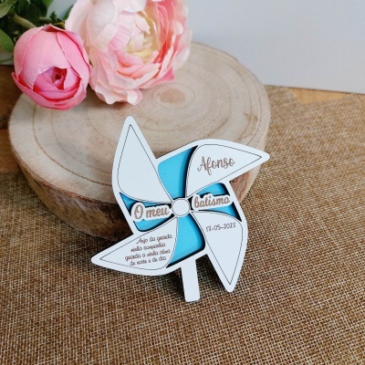 Pião de papel branco e azul com texto impresso sobre base de madeira com flores cor-de-rosa