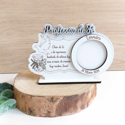 Porta-retrato branco de madeira com texto e desenho junto a um espaço para foto redondo, colocado sobre tronco de madeira com fundo claro.