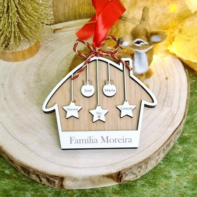 Enfeite de casa em madeira com nomes pendurados e fita vermelha, sobre base de madeira redonda