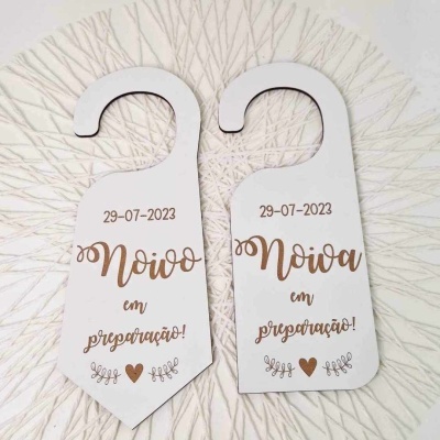 Penduradores de porta brancos com texto em castanho sobre um tapete redondo com padrão dourado