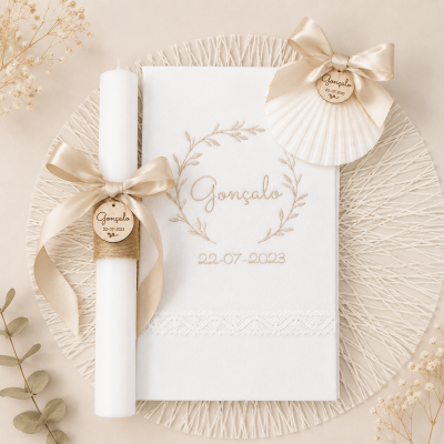 Conjunto de vela, toalha e concha decorados com nomes e data, em tons bege e branco