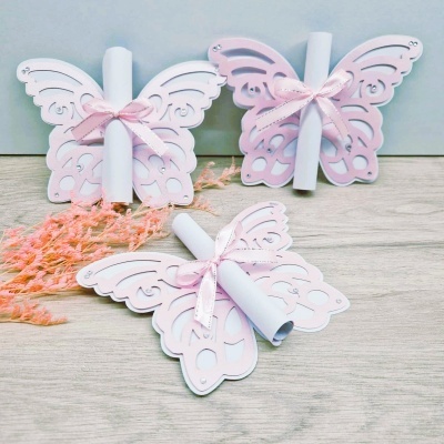 Convites de borboleta em papel rosa e branco com laços cor-de-rosa e rolos de papel branco