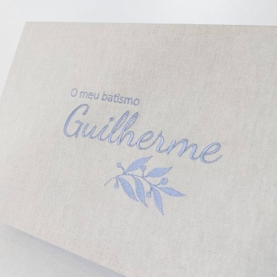 Pano bege bordado com texto azul e desenho de folhas