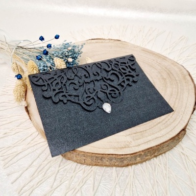 Envelope preto decorativo com padrão recortado a laser e botão de pedra