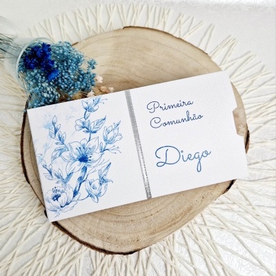Convite para Primeira Comunhão com ilustração azul e texto em papel branco sobre base de madeira