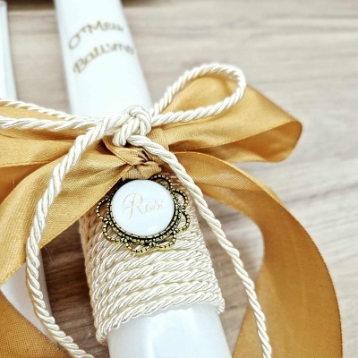 Vela decorada com laço dourado e medalhão com a palavra Rosa