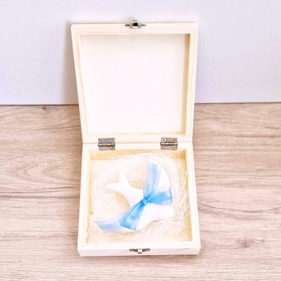 Caixa de madeira aberta com vela em forma de estrela do mar e laço azul