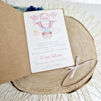 Convite para batismo com ilustração de balão de ar quente, nome Carolina e texto, sobre rodela de madeira