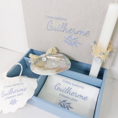 Itens para batismo com bordados azul claro e detalhes florais dentro de uma caixa azul