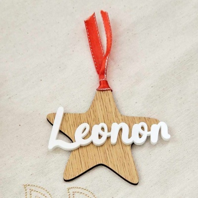 Estrela decorativa de madeira com nome 'Leonor' em branco e fita vermelha