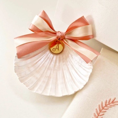 Concha decorada com laço rosa e creme e pendente dourado com letra A
