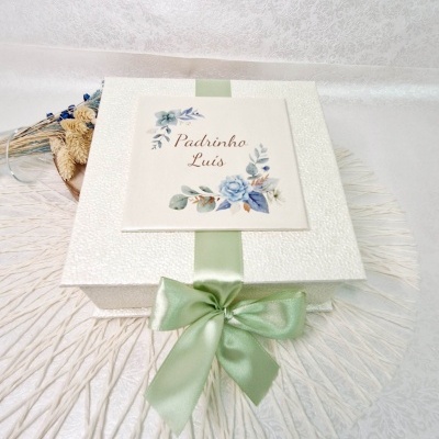 Caixa de presente branca com fita verde clara e etiqueta floral com texto 'Padrinho Luís'.