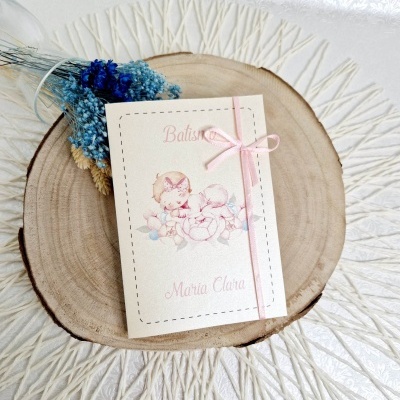 Convite de batismo com ilustração de crianças e flores em papel branco com laço rosa