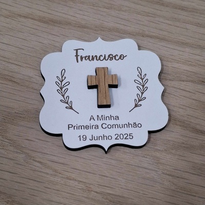 Cartão branco com cruz de madeira e texto sobre Primeira Comunhão, colocado numa mesa de madeira