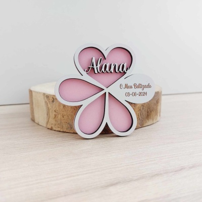Enfeite em forma de flor branca e rosa com nome Alana e texto O Meu Batizado 03-06-2024 sobre base de madeira