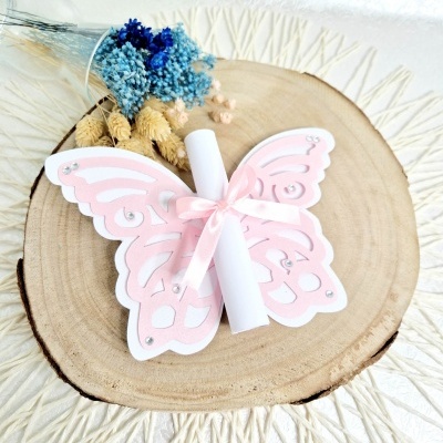 Laço borboleta de papel rosa com pergaminho sobre madeira com flores secas ao fundo