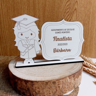 Trofeu decorativo de acrílico com figura de estudante e texto de finalista sobre base preta