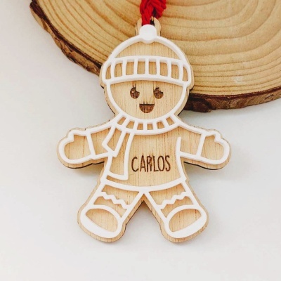 Enfeite de madeira em forma de boneco com detalhes brancos e nome Carlos