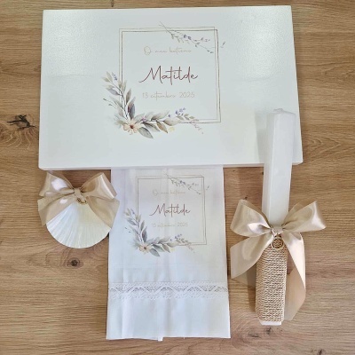 Conjunto de lembranças com caixa branca, concha com laço, pano bordado com nome e vela decorada.