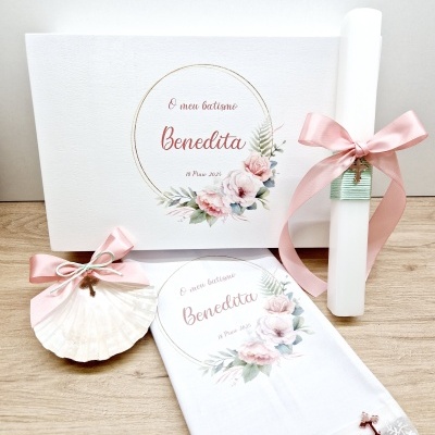 Conjunto de batismo com livro, toalha, concha decorada e pergaminho com fitas cor de rosa.
