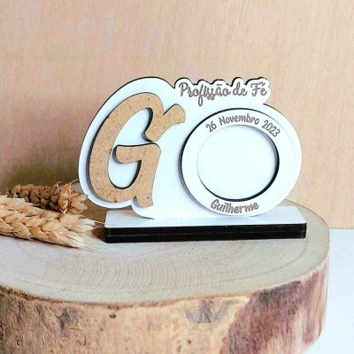 Objeto decorativo com letras em madeira, moldura circular para foto e base retangular sobre tronco de árvore