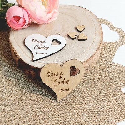 Duas peças de madeira em forma de coração gravadas, decoradas com flores, sobre madeira rústica